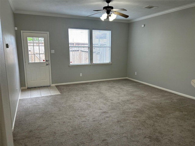 interior space featuring carpet flooring, visible vents, baseboards, a ceiling fan, and crown molding