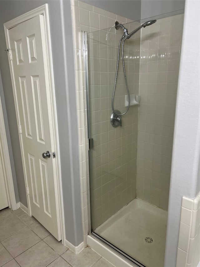 full bath featuring baseboards, tile patterned flooring, and a stall shower