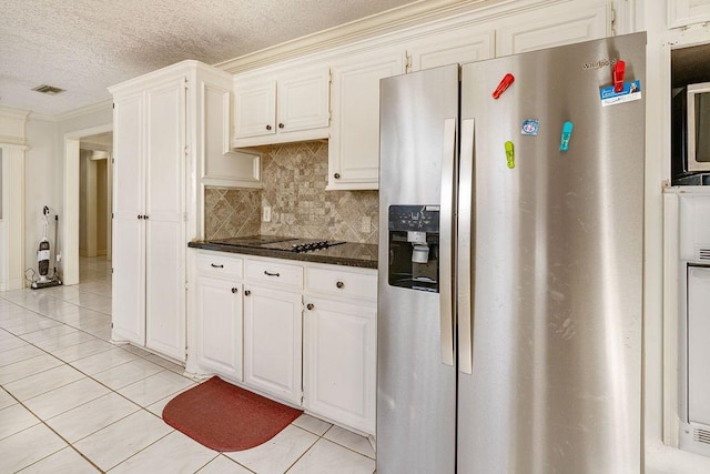 kitchen with crown molding, stainless steel fridge, white cabinets, a textured ceiling, and dark stone counters