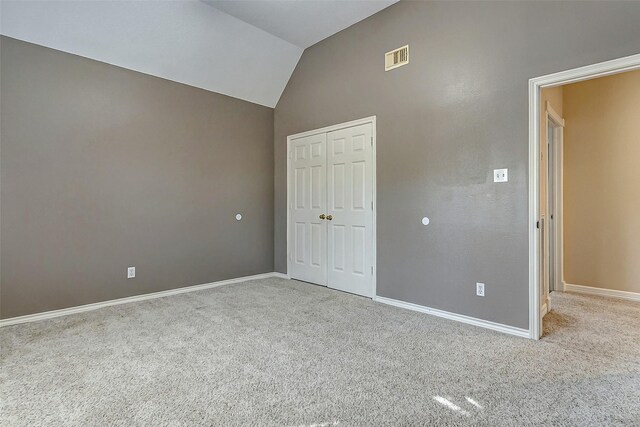 unfurnished bedroom featuring lofted ceiling, light carpet, and a closet