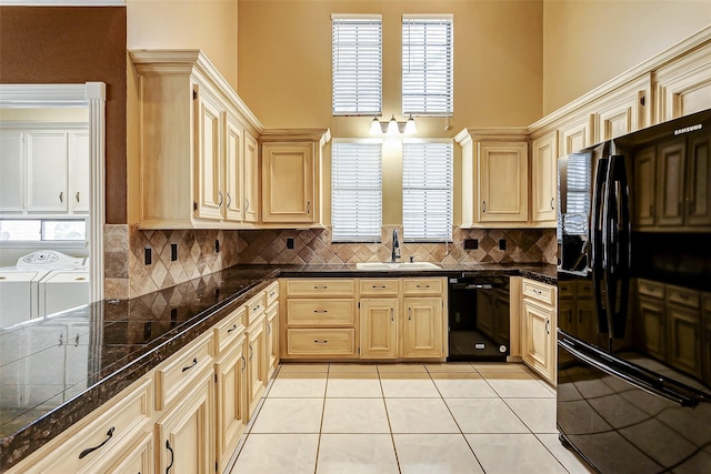 kitchen with sink, washing machine and dryer, black appliances, light tile patterned flooring, and light brown cabinetry