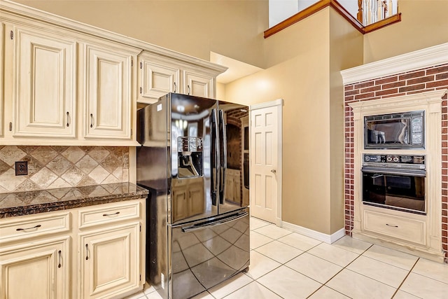 kitchen featuring light tile patterned flooring, cream cabinets, backsplash, and black appliances