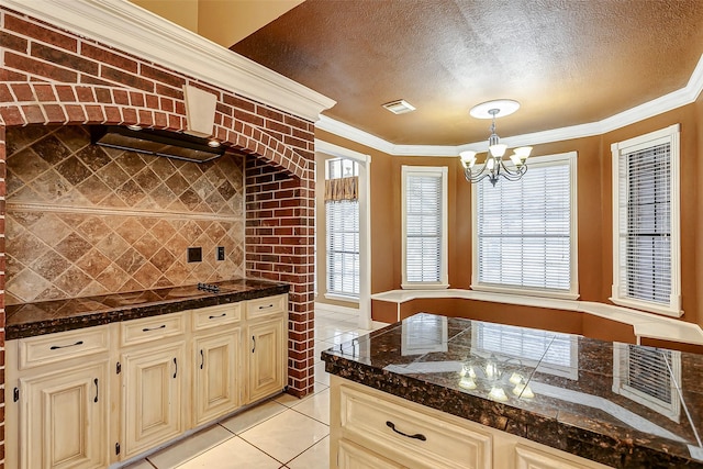 kitchen featuring light tile patterned flooring, decorative light fixtures, a chandelier, a textured ceiling, and ornamental molding