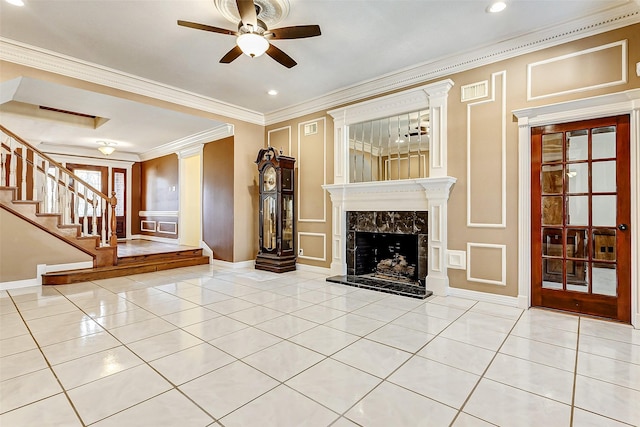 unfurnished living room with crown molding, light tile patterned flooring, ceiling fan, and a high end fireplace