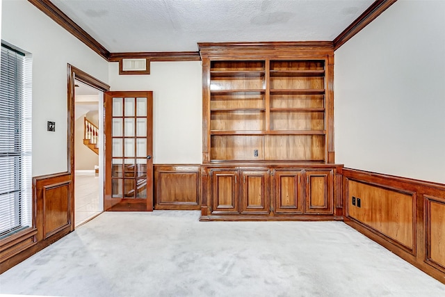 interior space with crown molding, wooden walls, a textured ceiling, and french doors