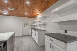 kitchen featuring white cabinetry, light wood-type flooring, sink, and wood ceiling