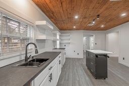 kitchen with wood ceiling, sink, hardwood / wood-style floors, and white cabinets