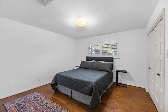 bedroom featuring baseboards, visible vents, and wood finished floors