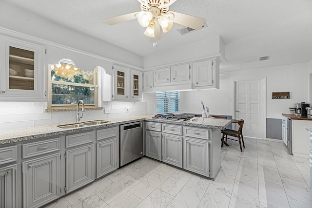 kitchen featuring glass insert cabinets, marble finish floor, a sink, and appliances with stainless steel finishes