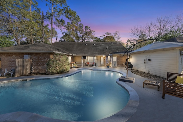 pool at dusk featuring a patio area