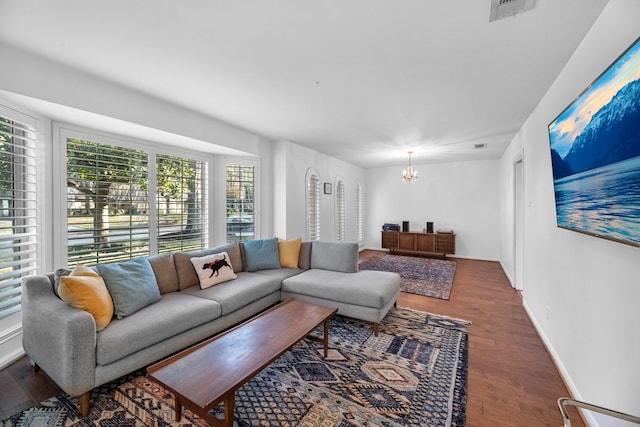 living room featuring baseboards, dark wood-type flooring, visible vents, and a notable chandelier