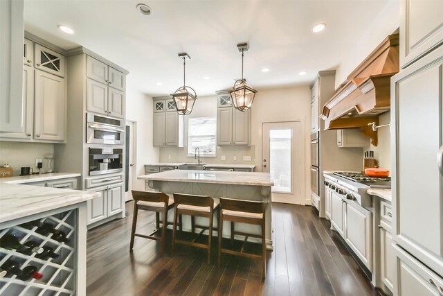 kitchen featuring dark hardwood / wood-style floors, sink, hanging light fixtures, stainless steel appliances, and light stone countertops