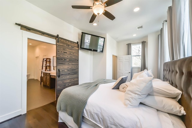 bedroom featuring a barn door, dark hardwood / wood-style floors, and ceiling fan