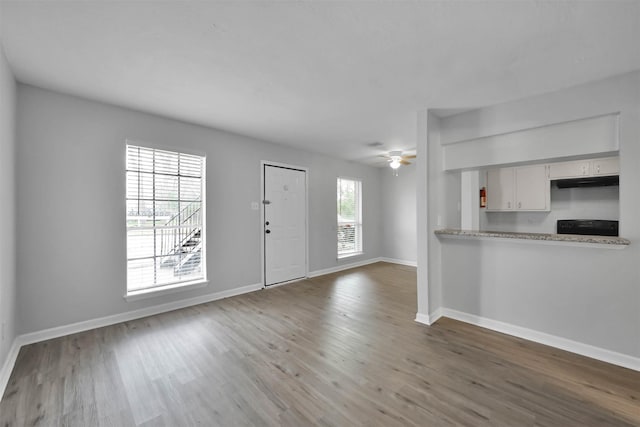 unfurnished living room with ceiling fan and wood-type flooring