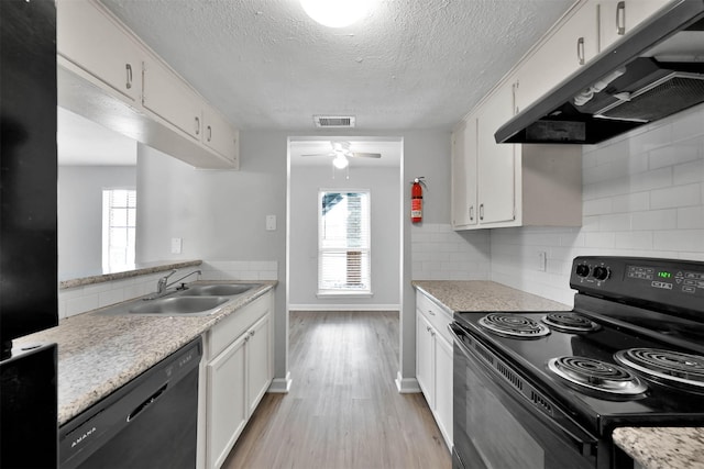 kitchen featuring a wealth of natural light, black appliances, light hardwood / wood-style flooring, white cabinets, and backsplash