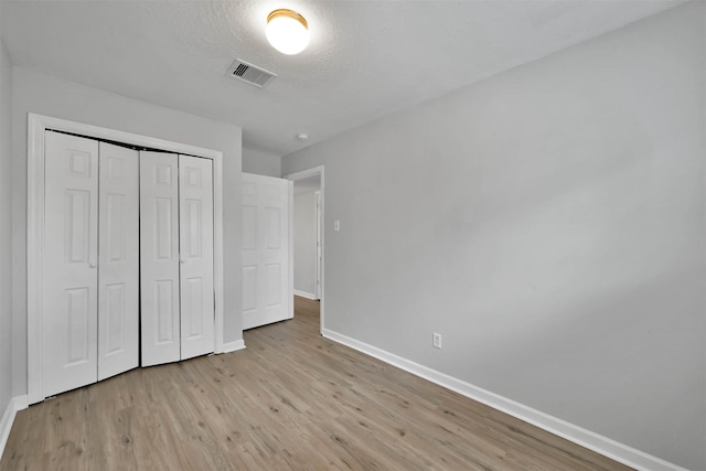 unfurnished bedroom featuring a closet, a textured ceiling, and light wood-type flooring