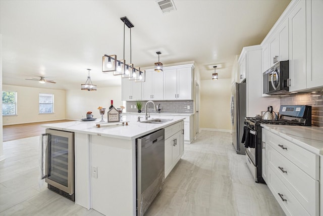 kitchen featuring pendant lighting, sink, white cabinetry, stainless steel appliances, and beverage cooler