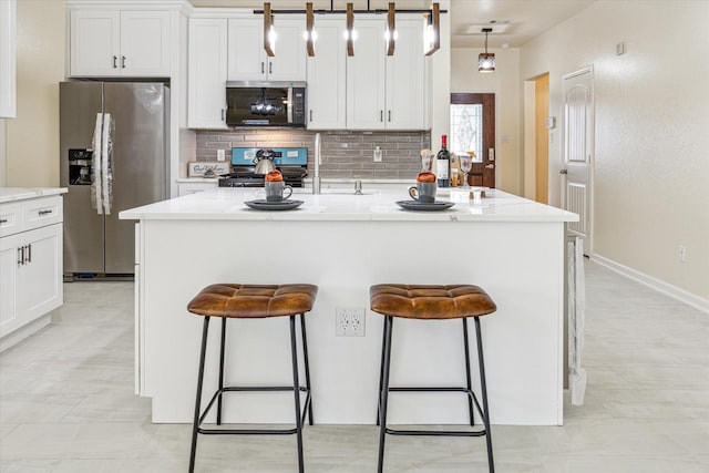 kitchen featuring hanging light fixtures, an island with sink, appliances with stainless steel finishes, and a kitchen breakfast bar