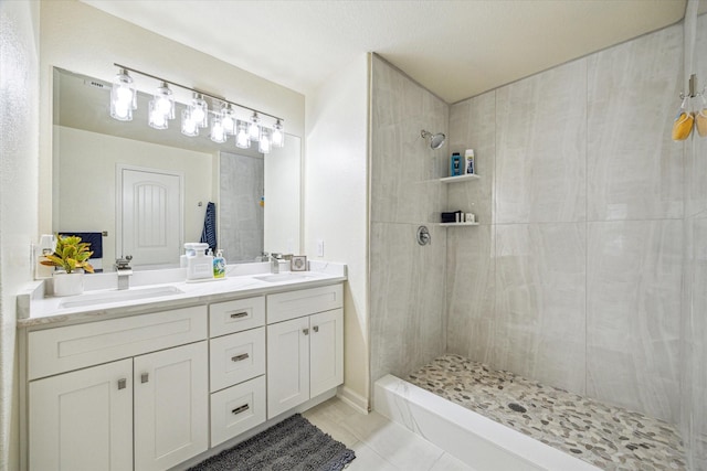 bathroom featuring vanity, a tile shower, and tile patterned floors