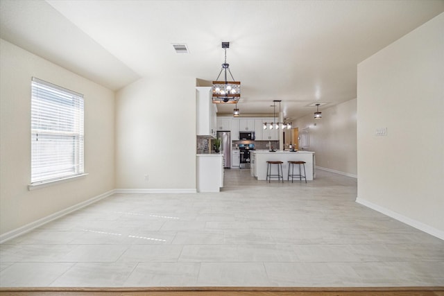 unfurnished living room featuring light tile patterned flooring, lofted ceiling, and an inviting chandelier