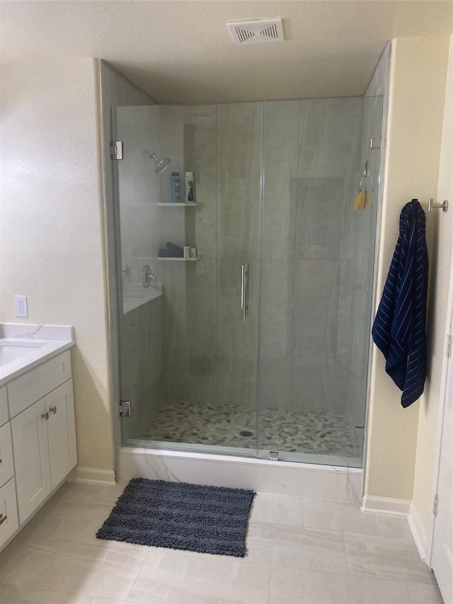 bathroom with tile patterned flooring, vanity, an enclosed shower, and a textured ceiling