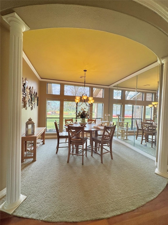 carpeted dining room featuring a healthy amount of sunlight, ornamental molding, decorative columns, and a notable chandelier