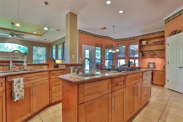 kitchen featuring a wealth of natural light, an island with sink, sink, hanging light fixtures, and stainless steel gas cooktop