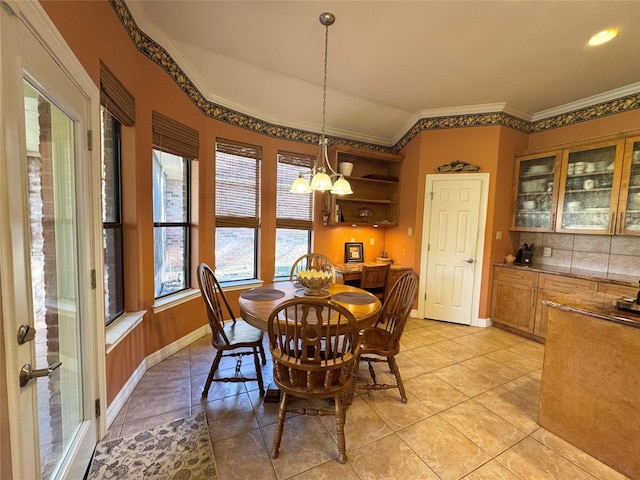 tiled dining area featuring crown molding, vaulted ceiling, and a notable chandelier