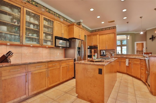 kitchen featuring appliances with stainless steel finishes, decorative light fixtures, decorative backsplash, a kitchen island with sink, and kitchen peninsula