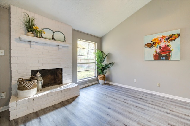 living room with lofted ceiling, a textured ceiling, a fireplace, and wood-type flooring