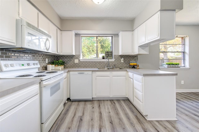 kitchen with sink, a textured ceiling, kitchen peninsula, white appliances, and white cabinets