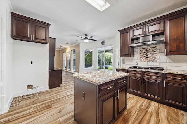 kitchen with ventilation hood, light stone countertops, stainless steel gas cooktop, and decorative backsplash