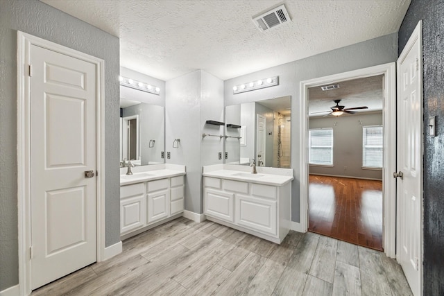 bathroom featuring vanity, ceiling fan, hardwood / wood-style flooring, and a textured ceiling