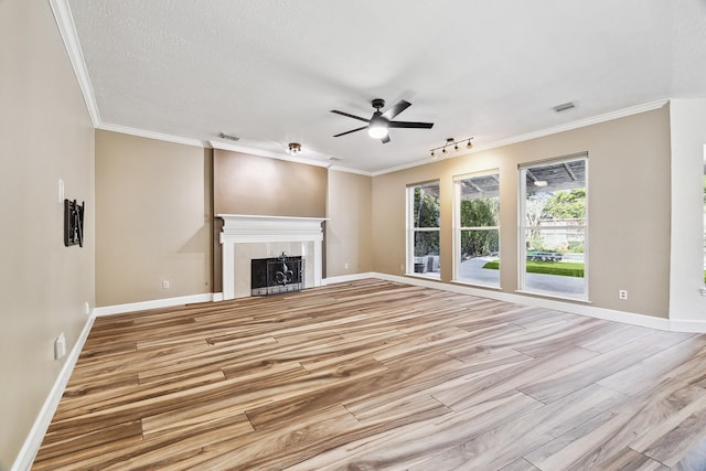 unfurnished living room featuring a textured ceiling, ornamental molding, rail lighting, and ceiling fan