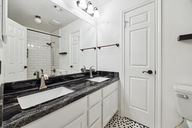 bathroom featuring vanity, toilet, and tiled shower