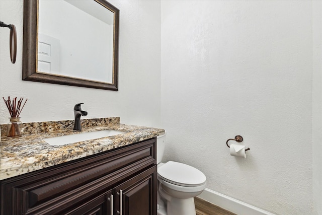 bathroom with vanity, toilet, and hardwood / wood-style floors