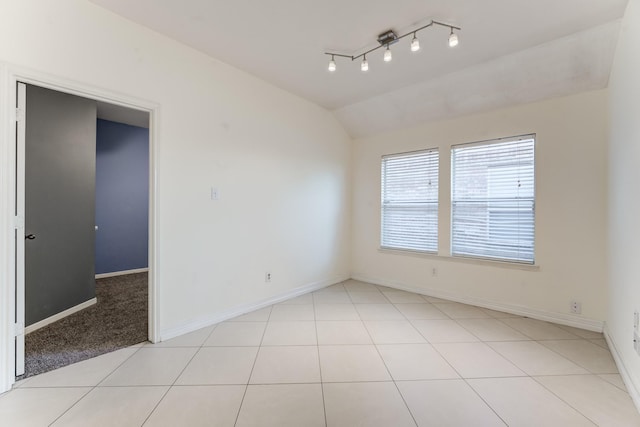 tiled empty room featuring vaulted ceiling