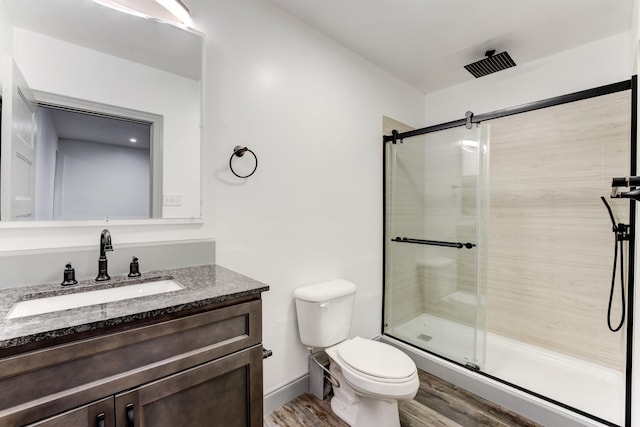 bathroom featuring vanity, toilet, a shower with shower door, and hardwood / wood-style floors