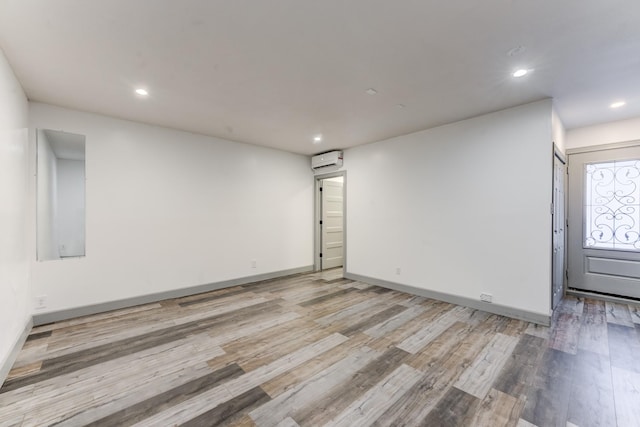 empty room featuring a wall mounted AC and light wood-type flooring