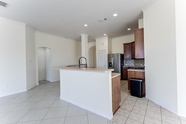 kitchen with stainless steel refrigerator with ice dispenser, sink, an island with sink, and decorative backsplash