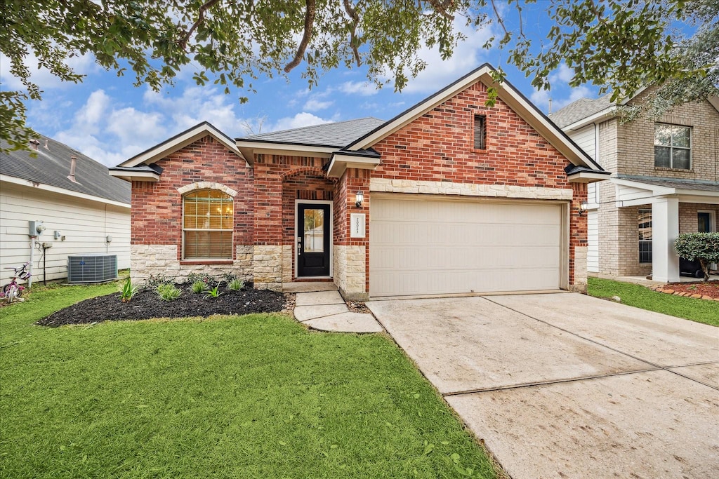 view of front of home featuring a garage, cooling unit, and a front lawn