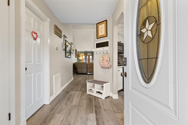 hallway with light hardwood / wood-style floors and a textured ceiling