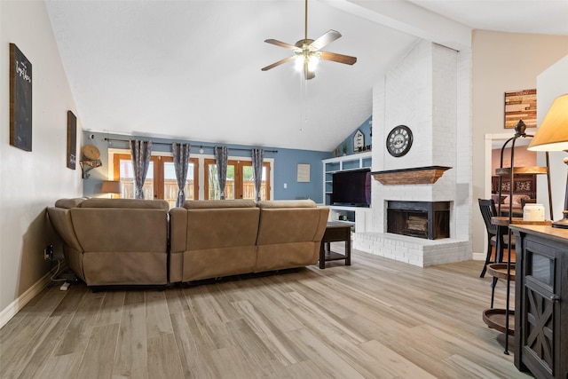 living room featuring ceiling fan, high vaulted ceiling, a fireplace, and light hardwood / wood-style floors