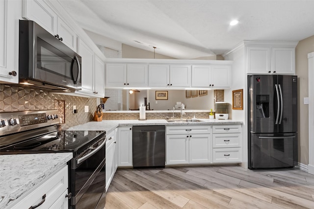 kitchen with lofted ceiling, sink, white cabinetry, appliances with stainless steel finishes, and decorative backsplash