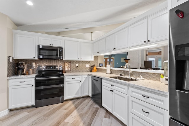 kitchen featuring sink, white cabinetry, vaulted ceiling, light hardwood / wood-style flooring, and stainless steel appliances