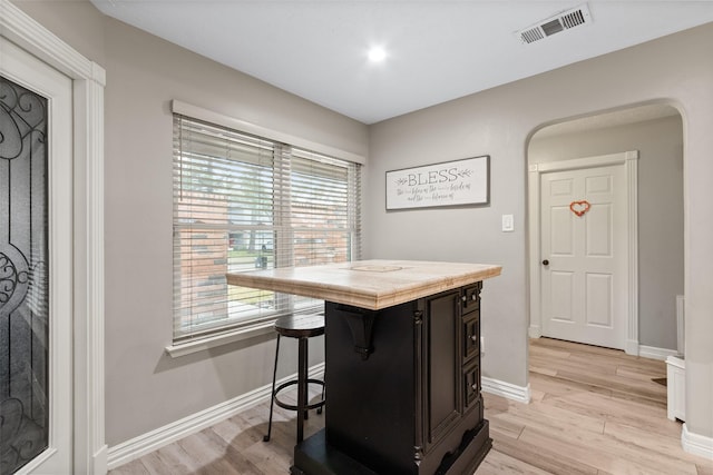 kitchen featuring a kitchen island, light hardwood / wood-style floors, plenty of natural light, and a kitchen bar