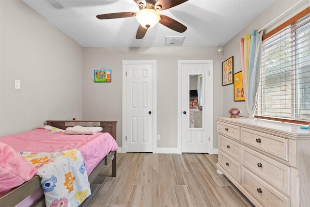 bedroom featuring a textured ceiling, light hardwood / wood-style floors, and ceiling fan