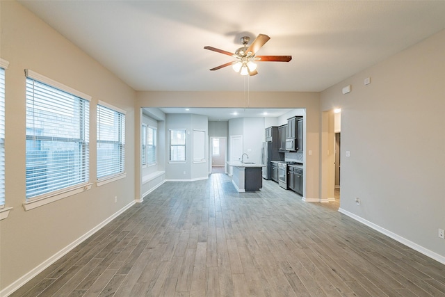 unfurnished living room featuring sink, hardwood / wood-style floors, and ceiling fan