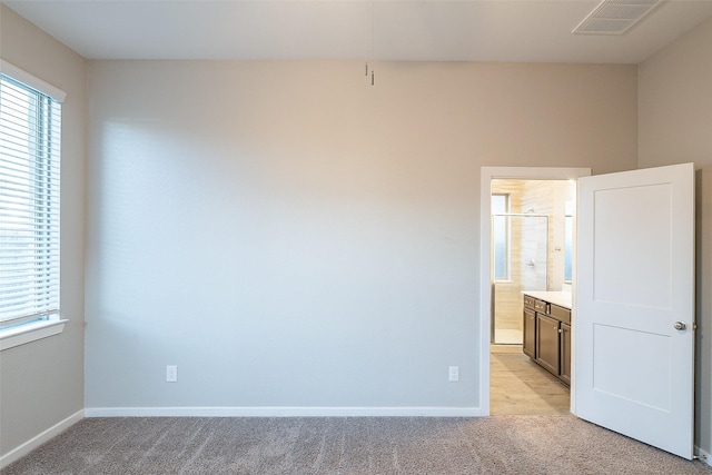 unfurnished bedroom featuring ensuite bath and light carpet