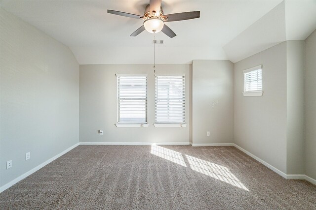 empty room featuring carpet floors, vaulted ceiling, and plenty of natural light